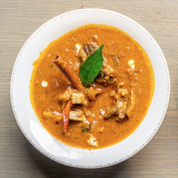 Bowl of Indian curry with meat, paneer, a cinnamon stick, and a bay leaf.